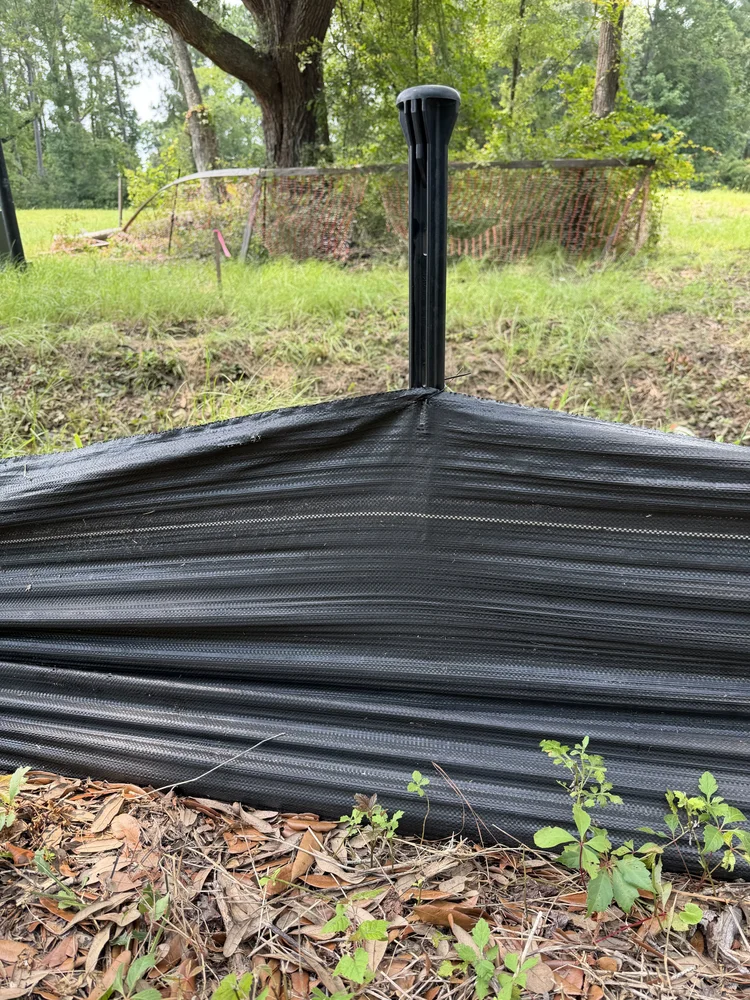 Close view of a Badger stake supporting black silt fence fabric